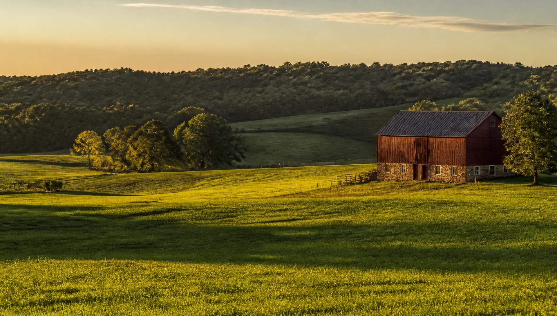 Rolling farmland and a red barn at golden hour on the Maryland–Pennsylvania line